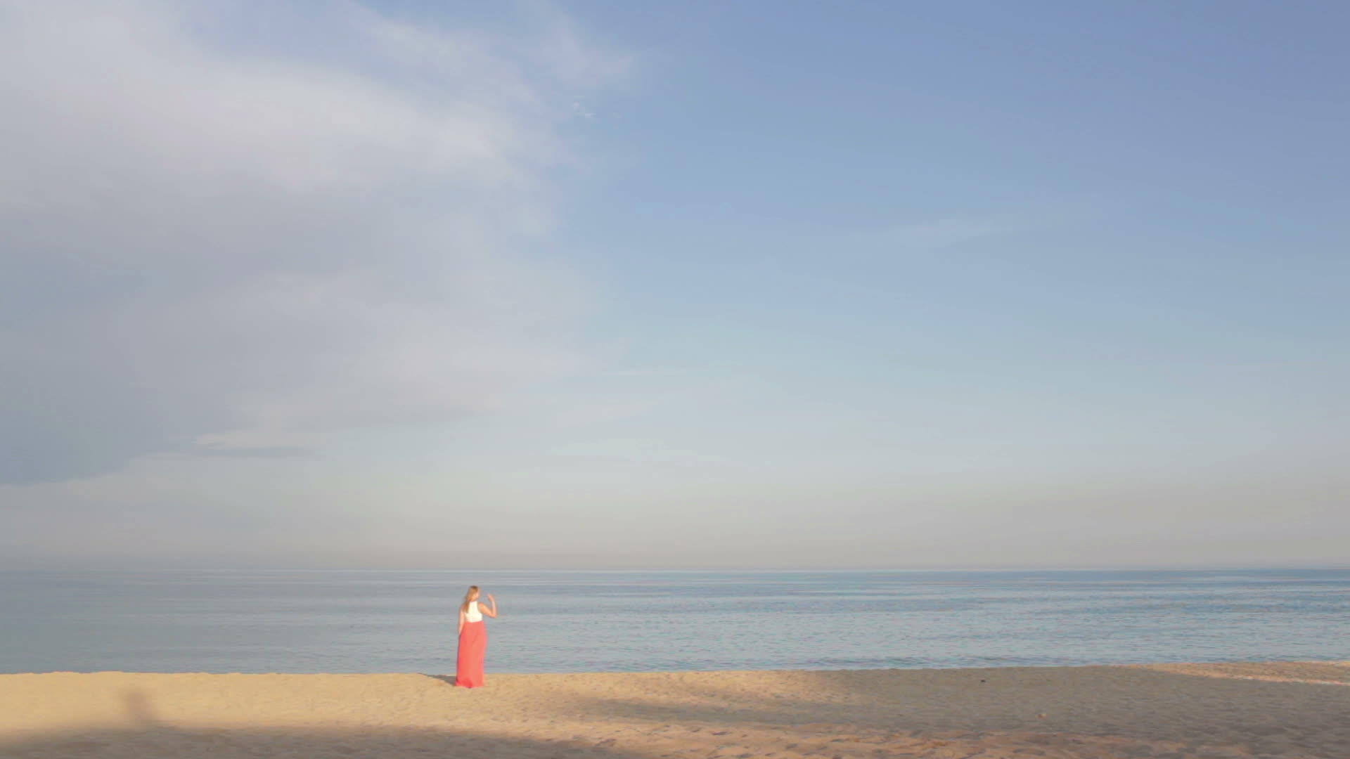 穿着橙色裙子的女孩说再见海边然后走开视频的预览图
