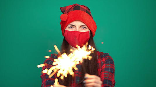 戴着烟花爆竹和圣诞帽的漂亮女人戴着防护面具视频的预览图