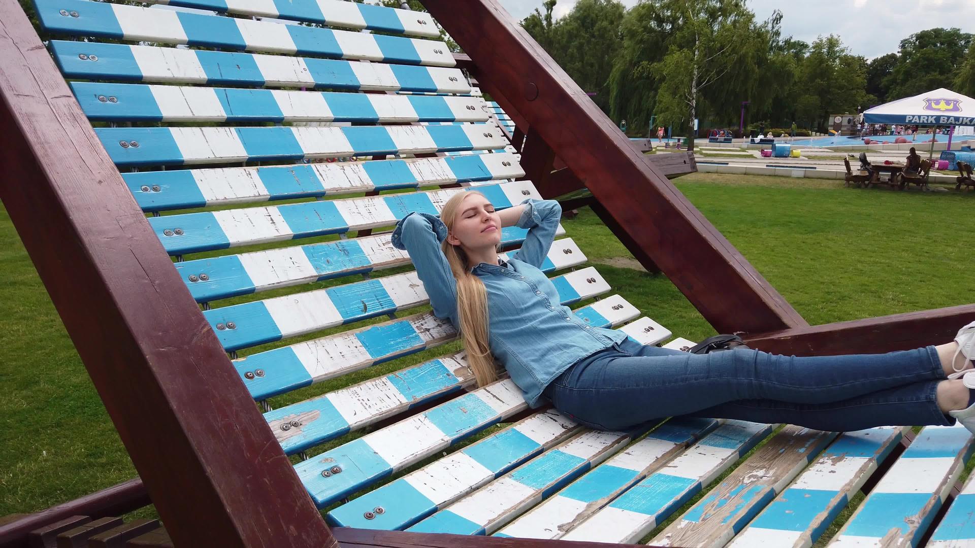 女孩躺在公园里一把很大的甲板椅上视频的预览图