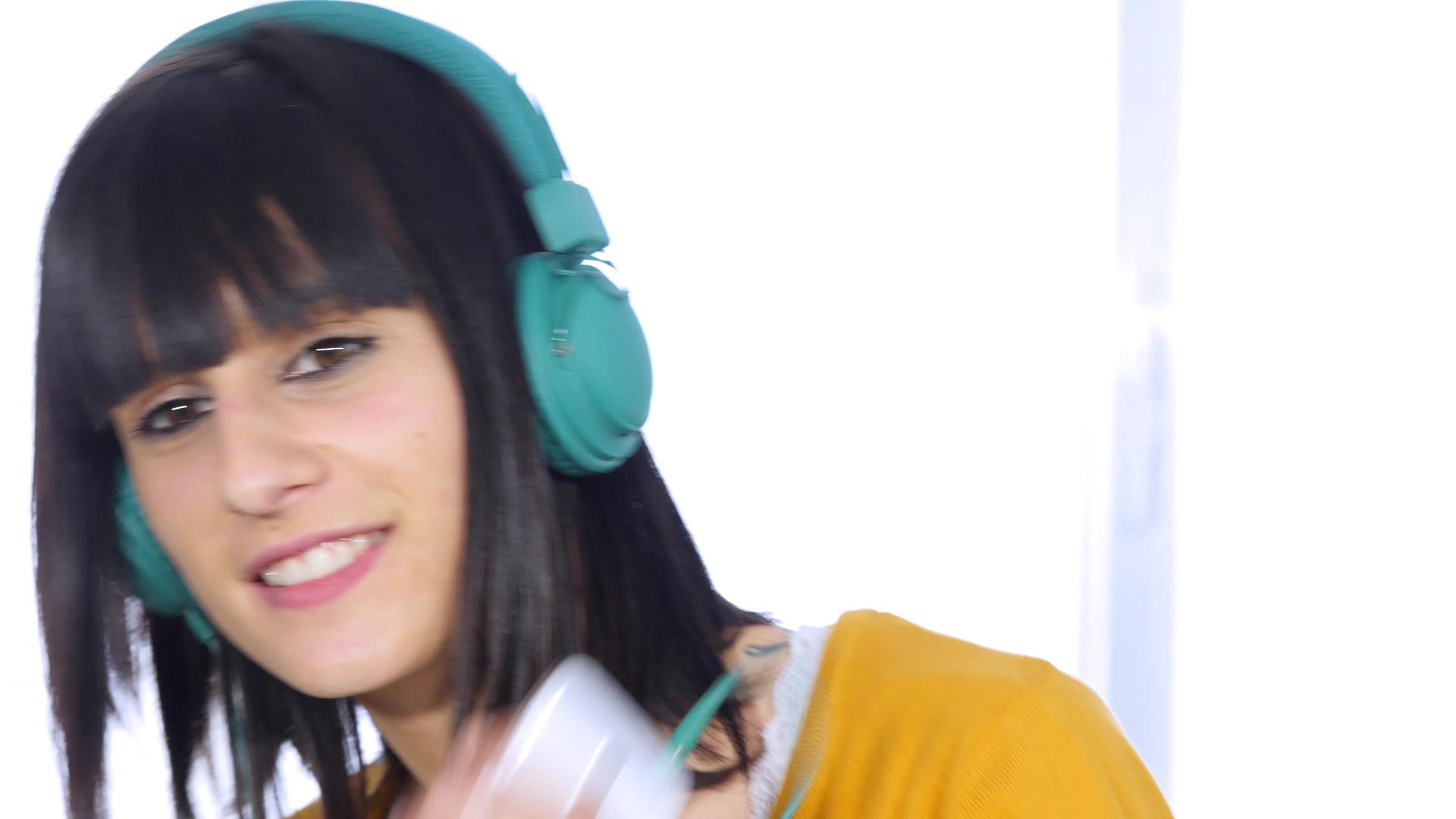 年轻女孩戴着绿色耳机听音乐视频的预览图