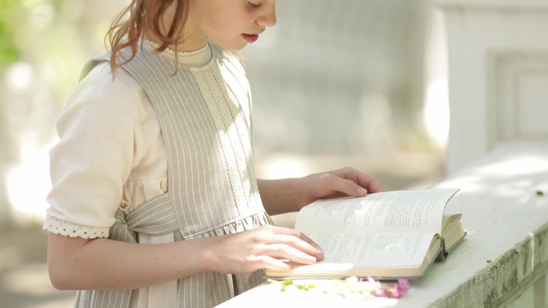 一个有马尾辫的女孩在公园里读一本书视频的预览图