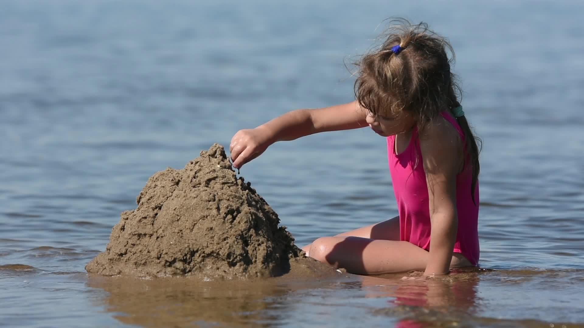 一个女孩在河的浅水中挖了很多沙子视频的预览图