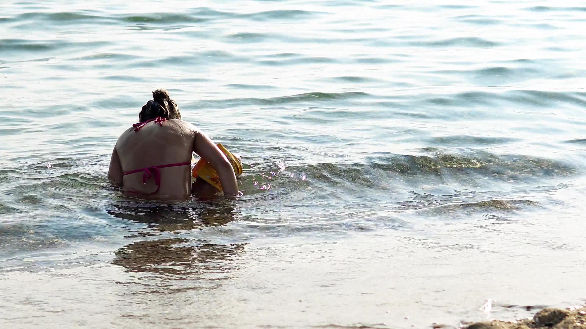 暑假期间孤独的小女孩独自在海里玩耍视频的预览图