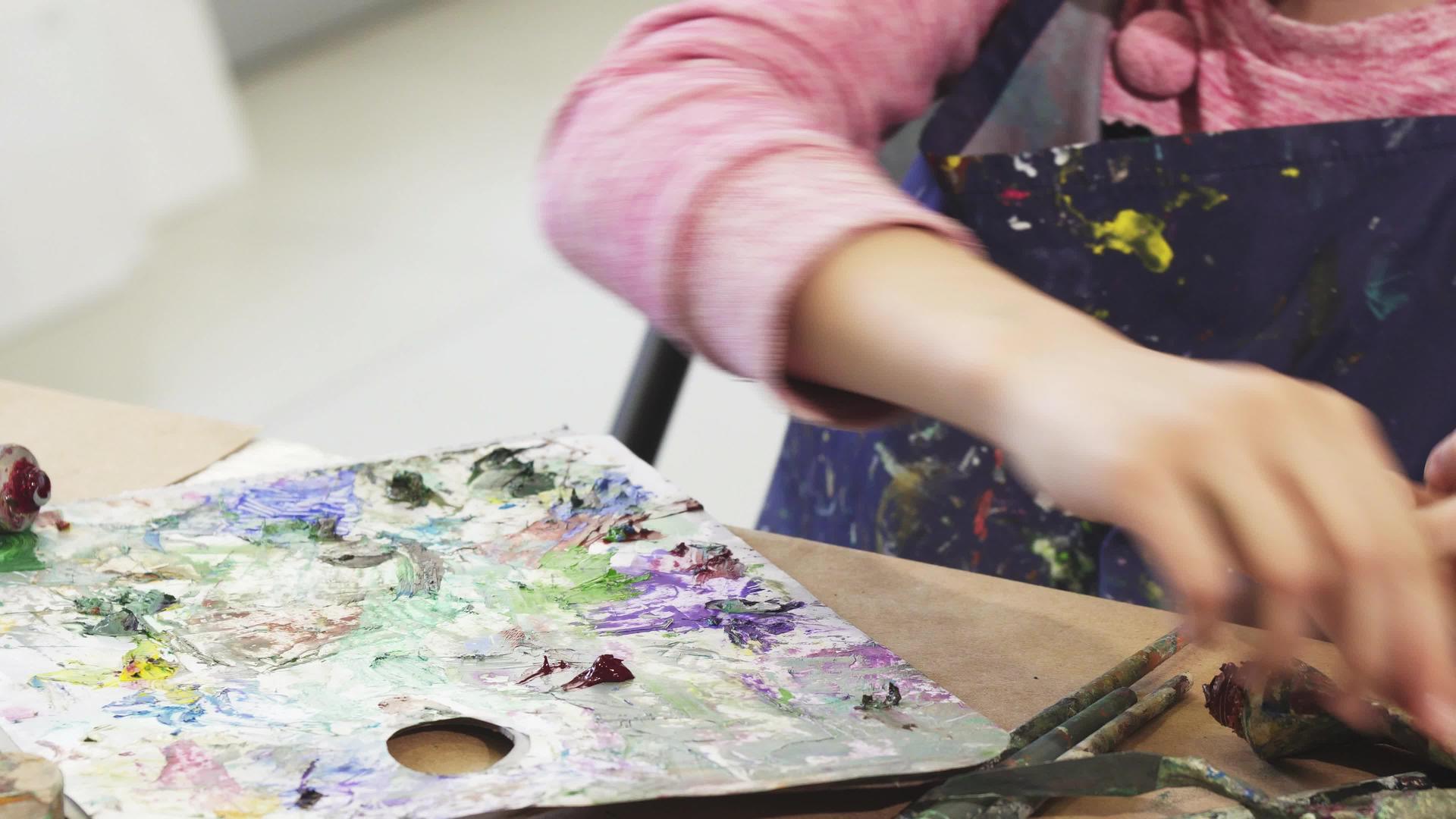 一个女孩从管子上挤油漆到调色板视频的预览图