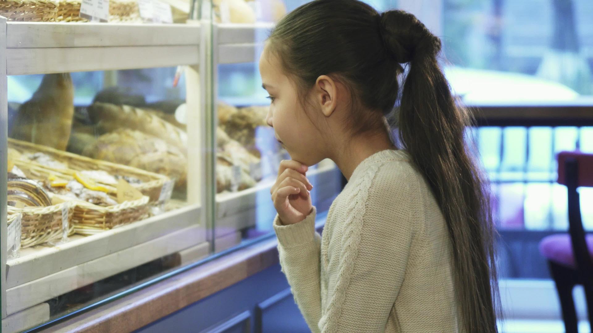 可爱的小女孩看着当地面包店的摊位视频的预览图