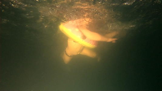 有充气环的女孩在黑暗恐怖池的水下慢动作中游泳视频的预览图