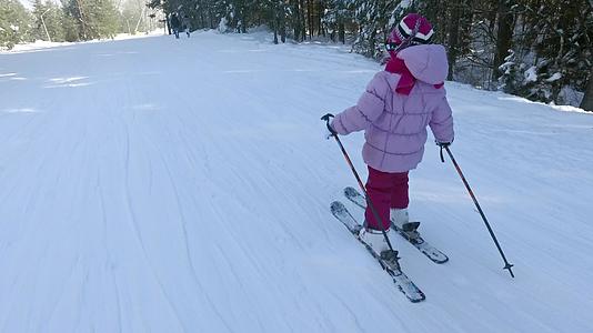 在斜坡上学习滑雪的小女孩视频的预览图
