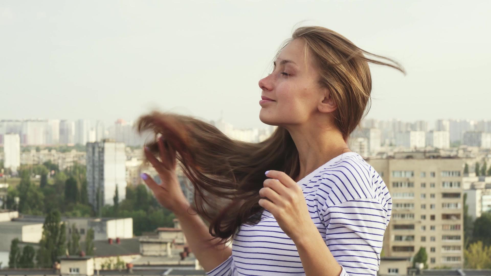 站在屋顶上的年轻女孩享受着天气的味道视频的预览图