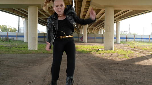 一个年轻的朋克女孩在城市的汽车桥下跳舞身穿黑色摄像头视频的预览图