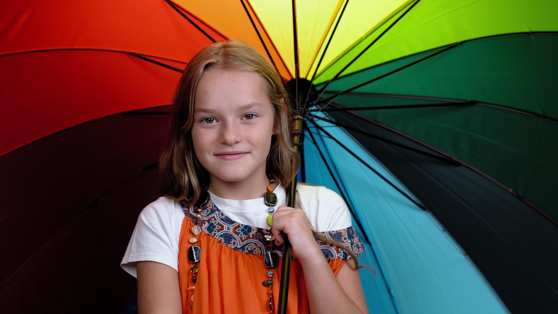 一个10岁的女孩看着工作室里五颜六色的彩虹伞手里拿着一把彩虹伞视频的预览图