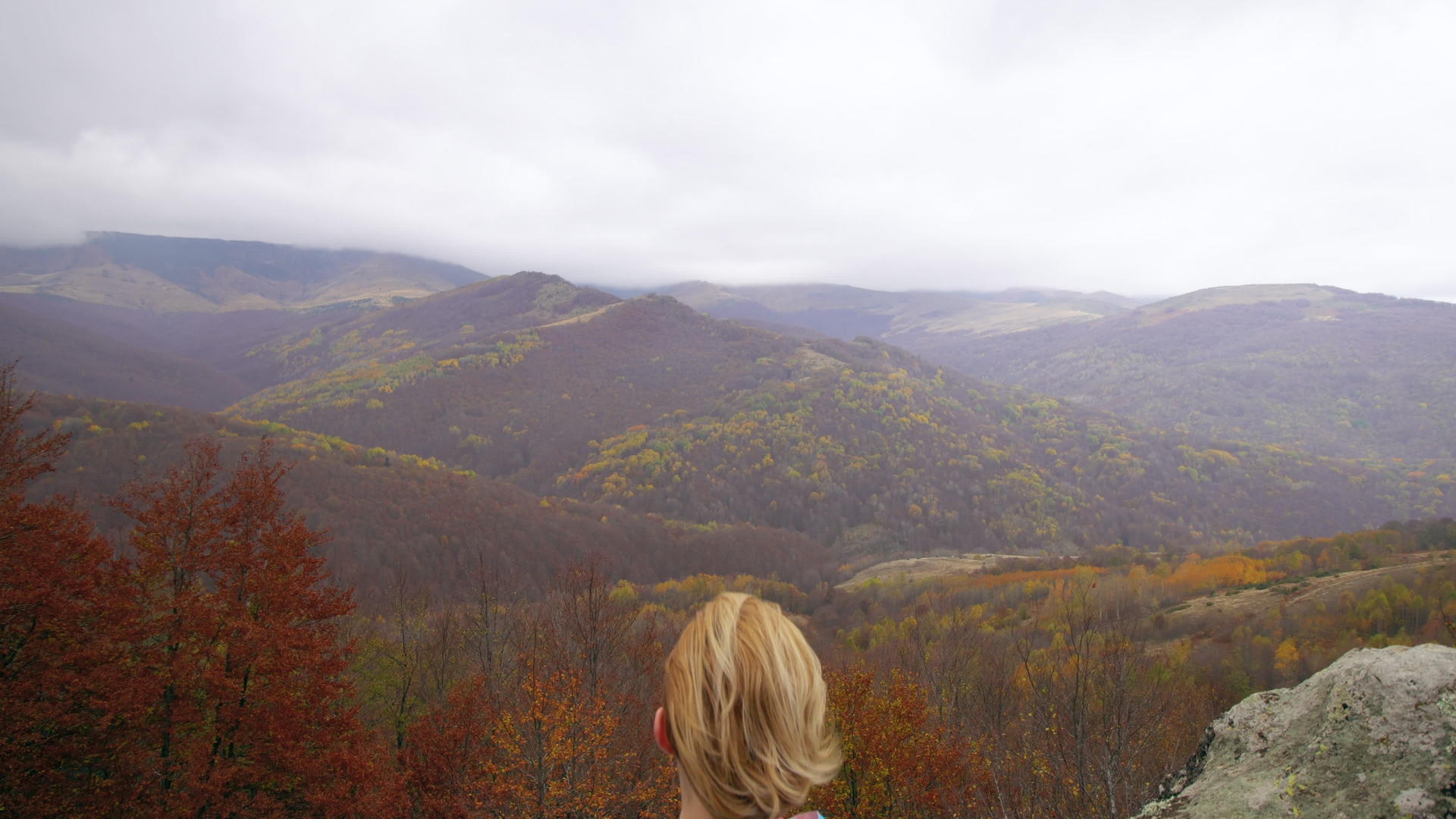 蓝色女性徒步旅行者在山上的岩石上享受多云的日子视频的预览图