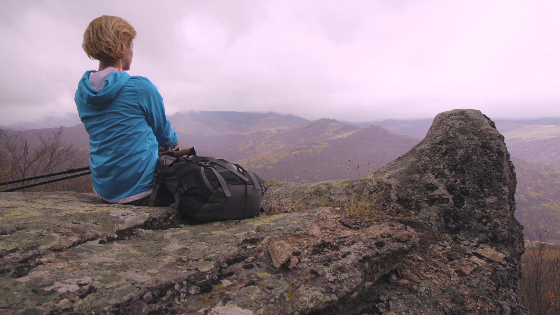 蓝色女性徒步旅行者在山上的岩石上休息视频的预览图