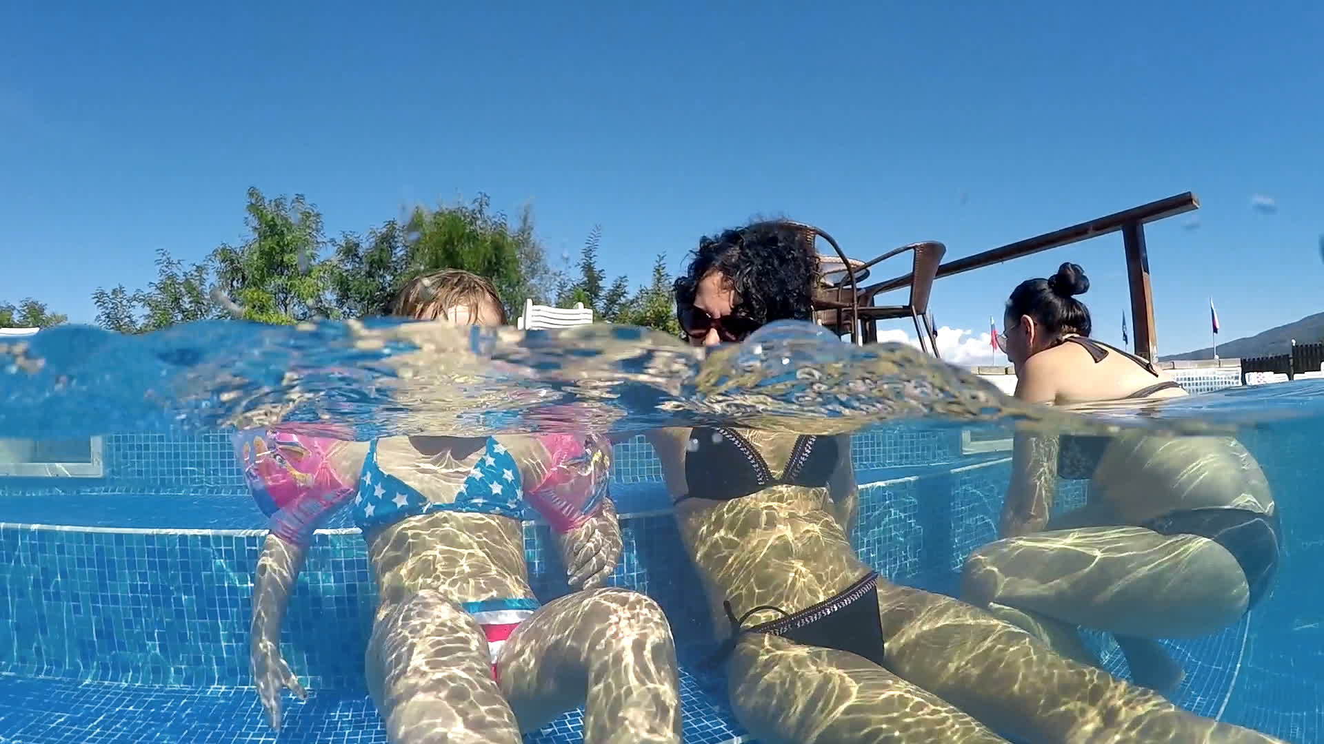 一个小女孩一家人在温泉池里游泳用充气臂章漂浮在水面上视频的预览图