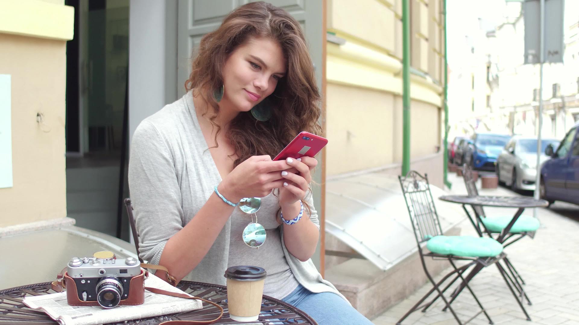 头发卷曲的年轻女性旅行者在智能手机上打字视频的预览图
