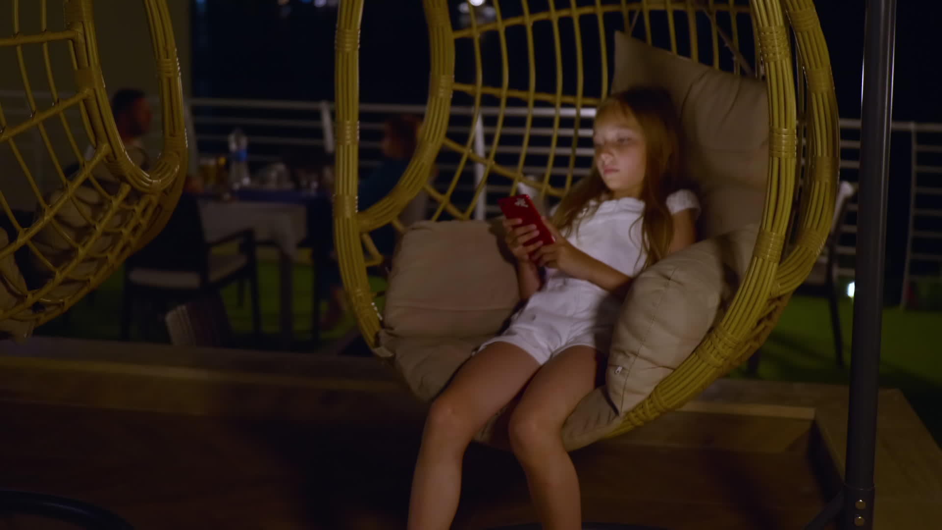 可爱的十几岁的女孩用智能手机睡在椰子摇椅上视频的预览图