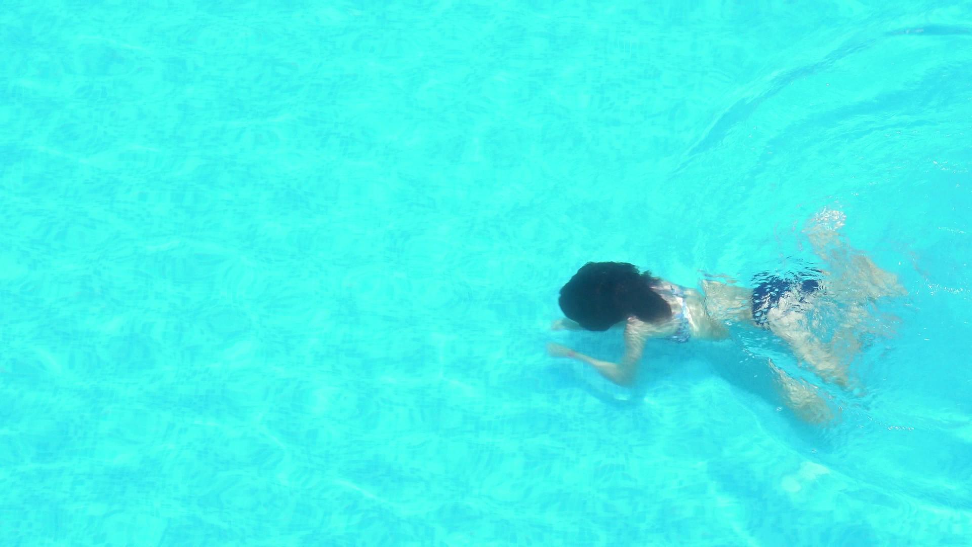 年轻女子在清澈的游泳池里游泳视频的预览图
