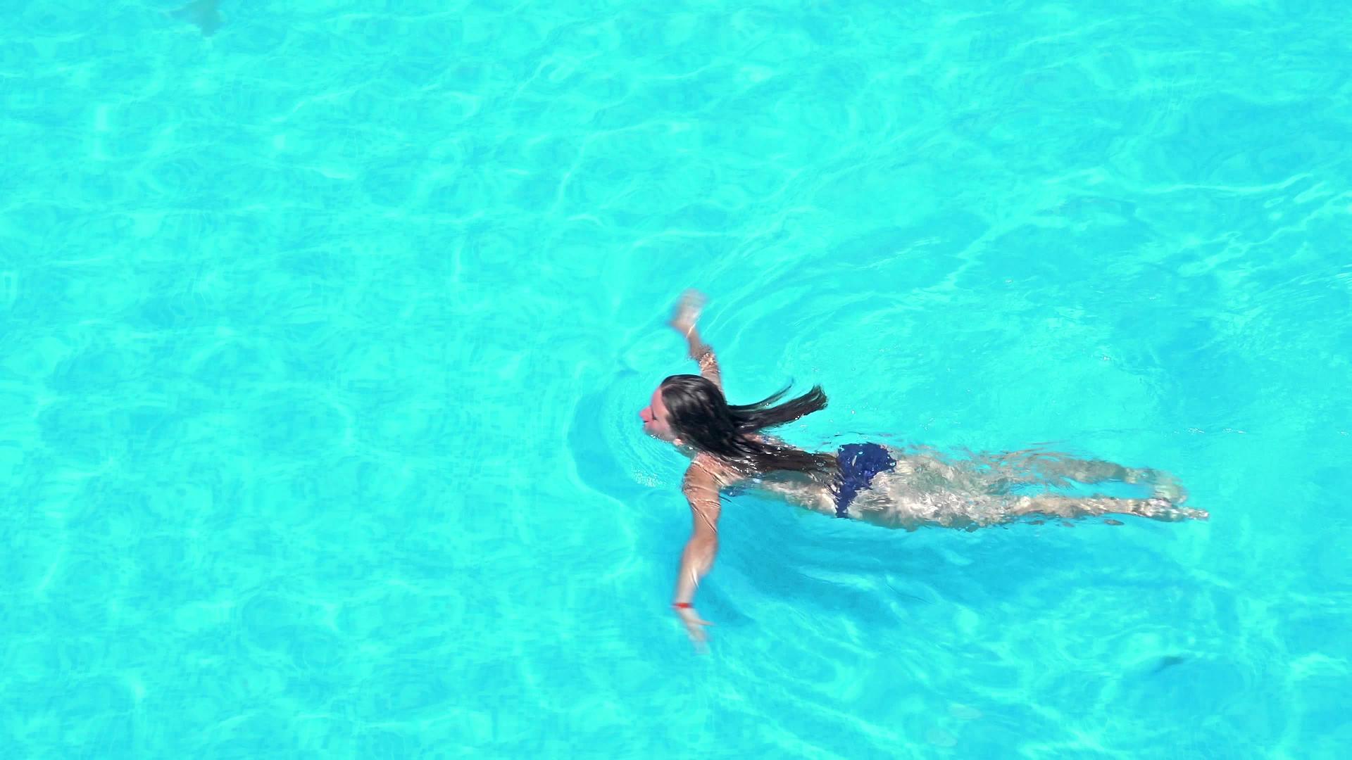 女孩在游泳池游泳4k航拍视频的预览图