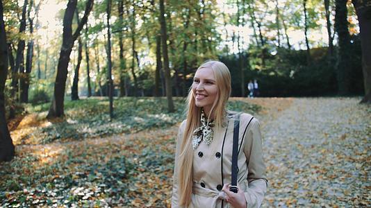 秋天年轻的金发女孩在公园里散步视频的预览图