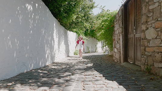 在阳光明媚的街道上行走的旅游女孩夏天的老城镇充满了岩壁视频的预览图