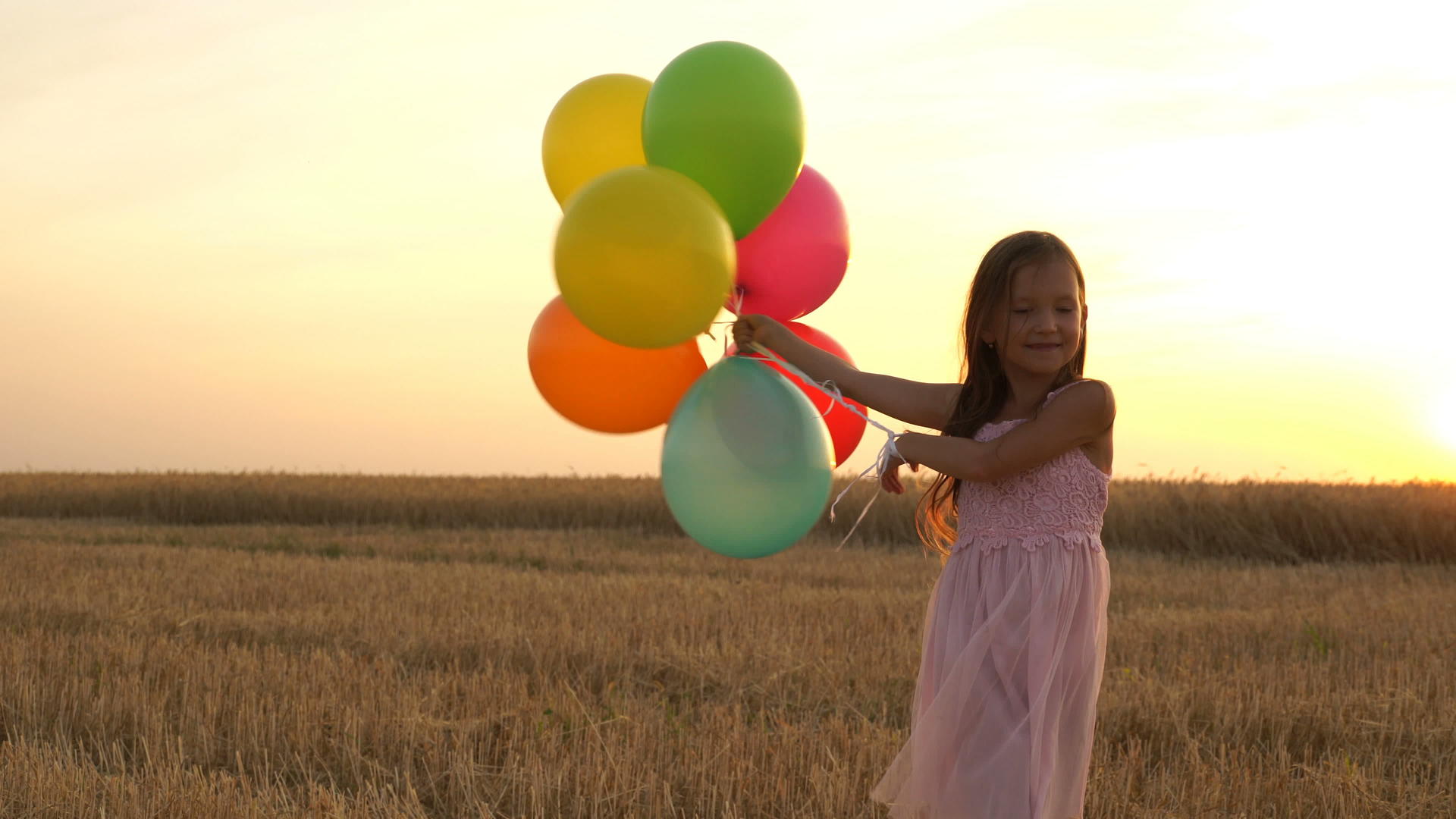 女孩用气球在田里行走视频的预览图