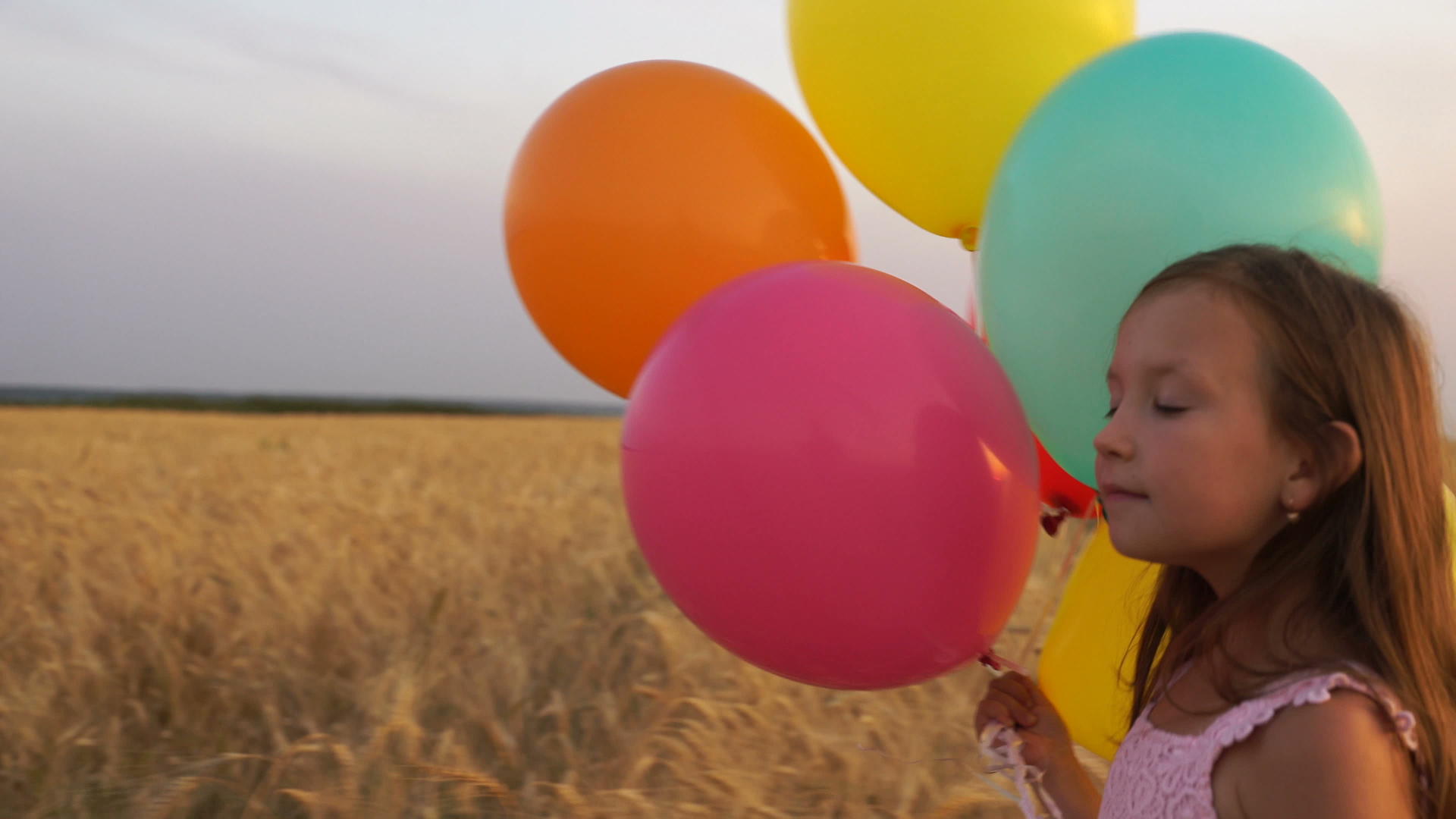 女孩用气球在田里行走视频的预览图