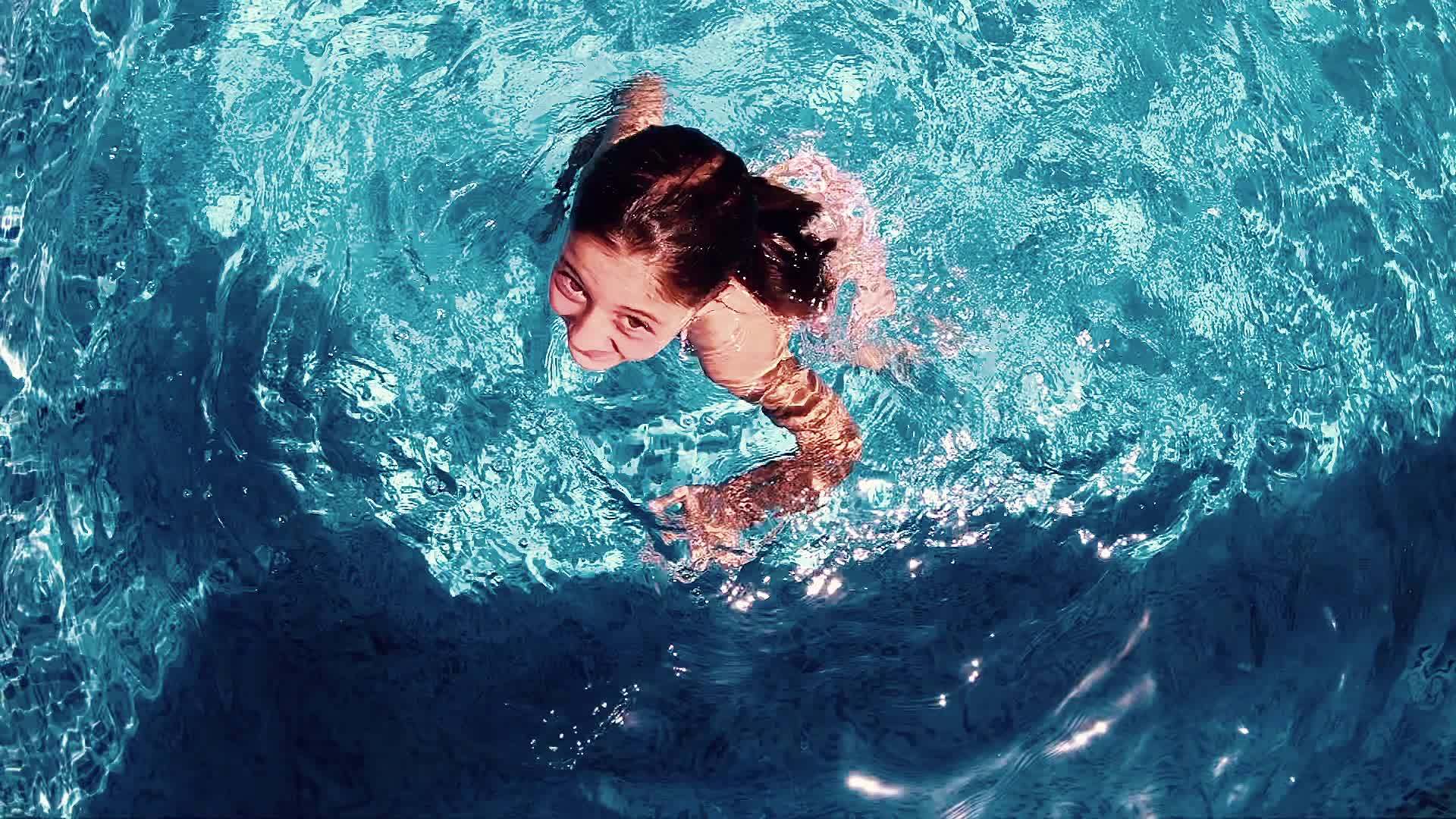 快乐可爱的小女孩在游泳池里对着相机微笑视频的预览图