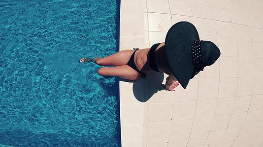 游泳池顶层的黑帽子和比金尼女人视频的预览图