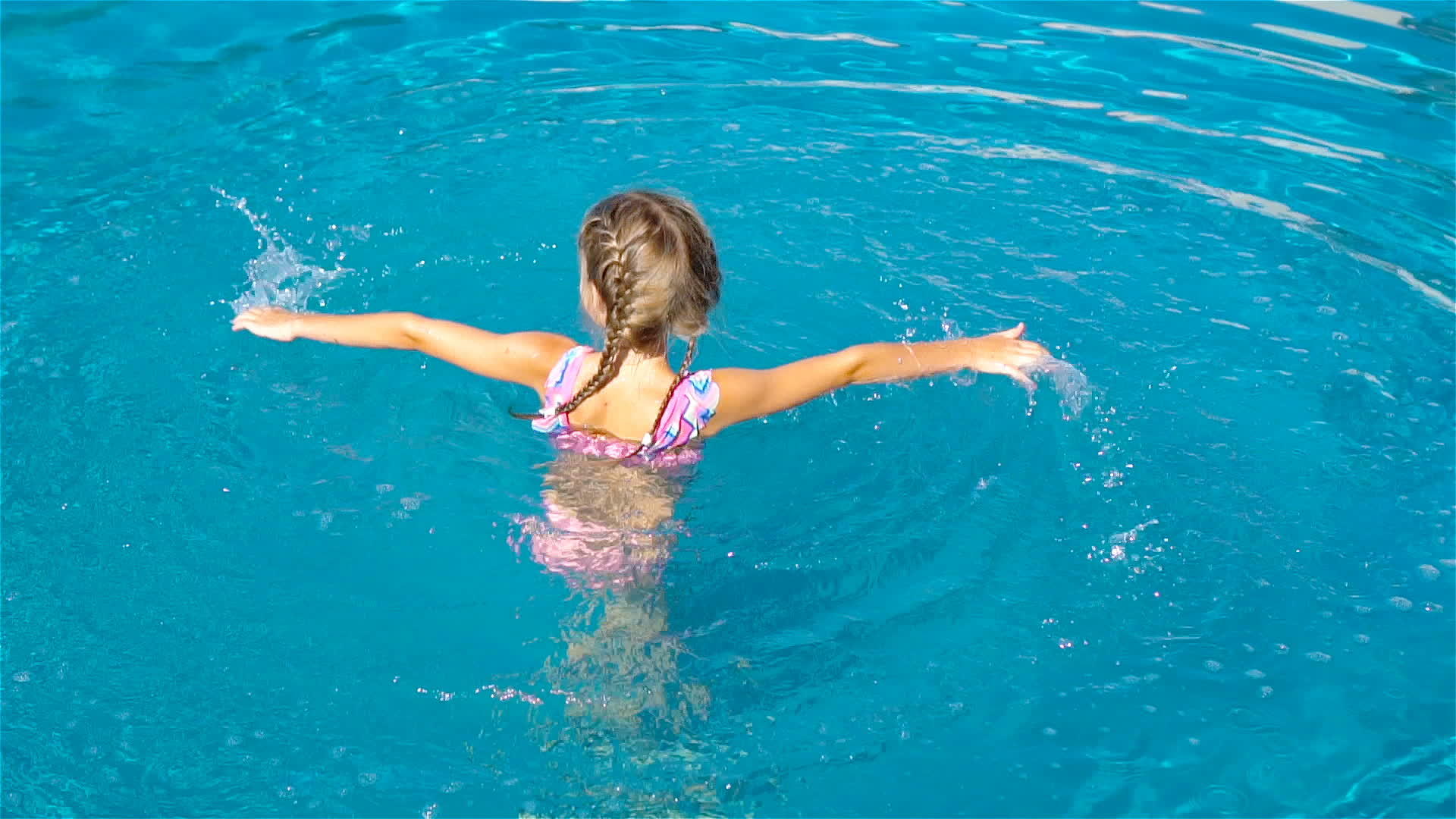 可爱的小女孩在户外游泳池里视频的预览图