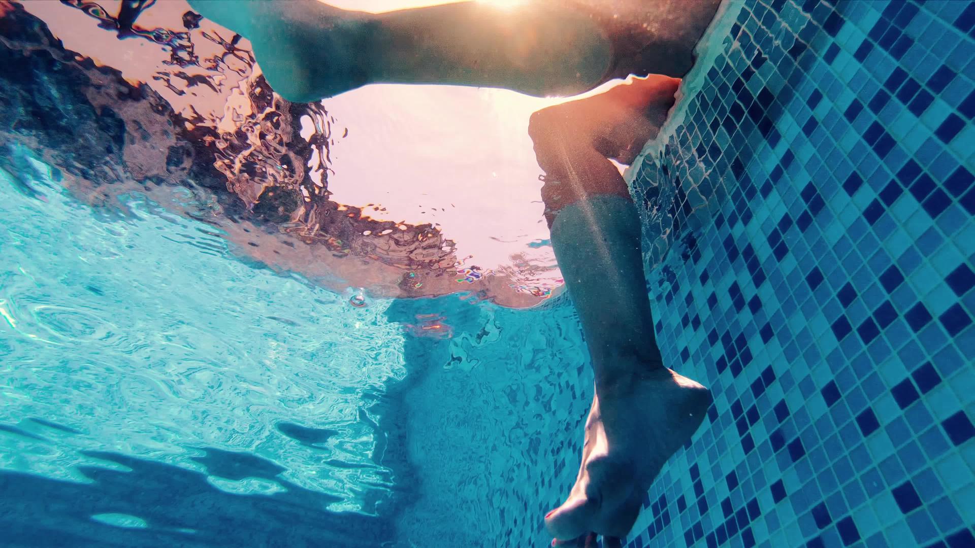 女人坐在游泳池边腿在游泳池水下视频的预览图