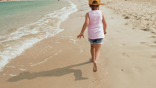 可爱的小女孩在海滩上奔跑视频的预览图