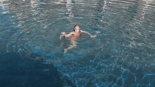 可爱的女孩穿着泳衣和护目镜在户外游泳池休息视频的预览图