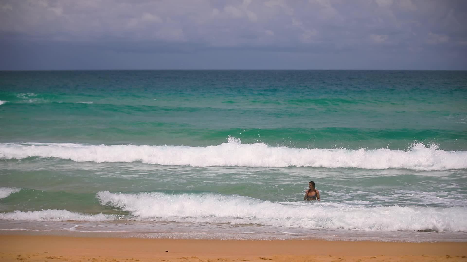 美丽的年轻女孩沐浴在海浪中视频的预览图
