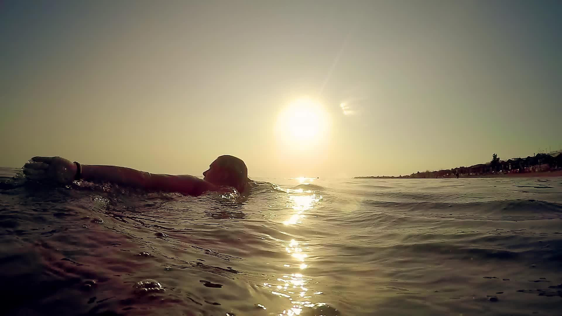 快乐的女孩在日落时在海里游泳和喷水视频的预览图