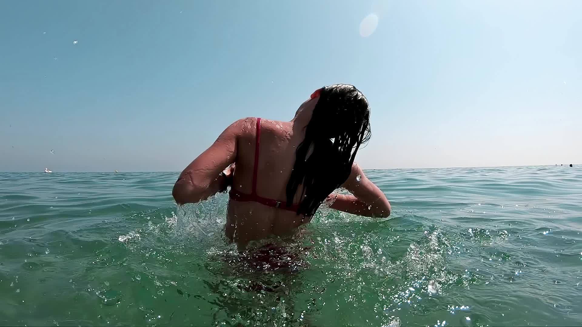 女孩在海里跳起来试图拉开她的耳朵慢慢移动视频的预览图