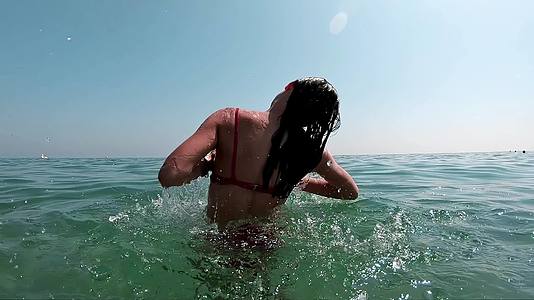 女孩在海里跳起来试图拉开她的耳朵慢慢移动视频的预览图