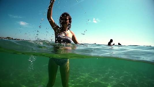 快乐的笑女孩站在海里戴着漂浮的面具挥舞着海水Gopro视频的预览图