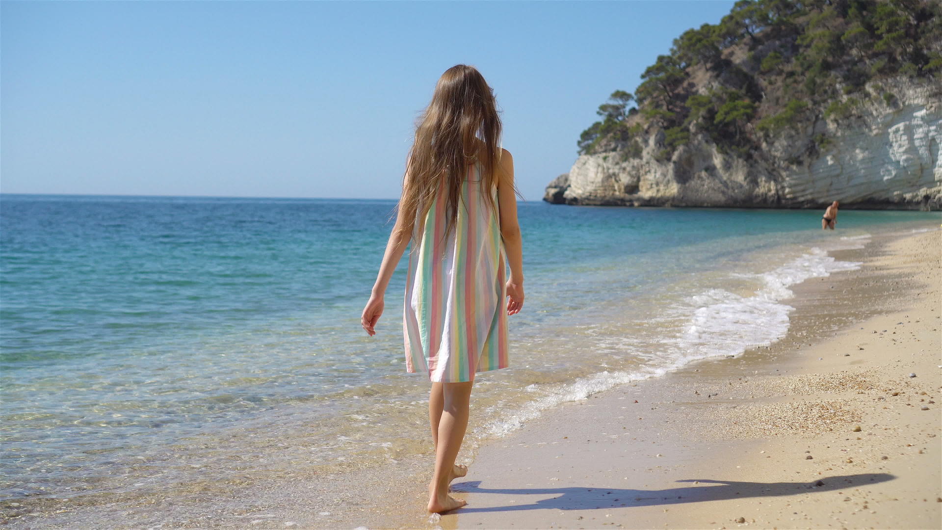 一个穿着漂亮衣服的小女孩在海滩上玩得开心有趣视频的预览图