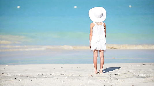 一个穿着白色衣服的小女孩在卡利比恩度假的海滩上视频的预览图