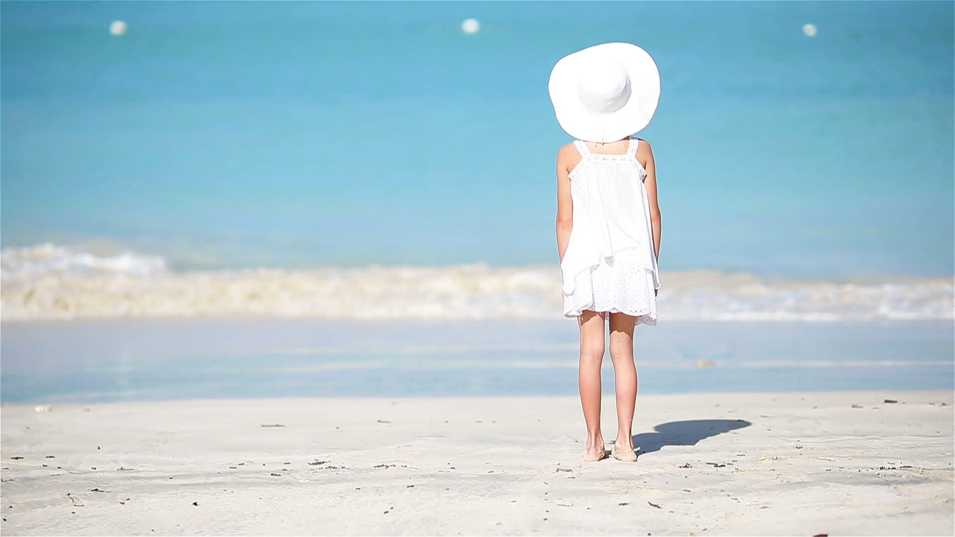 可爱的小女孩在卡利比恩度假的海滩上穿着白色的衣服视频的预览图