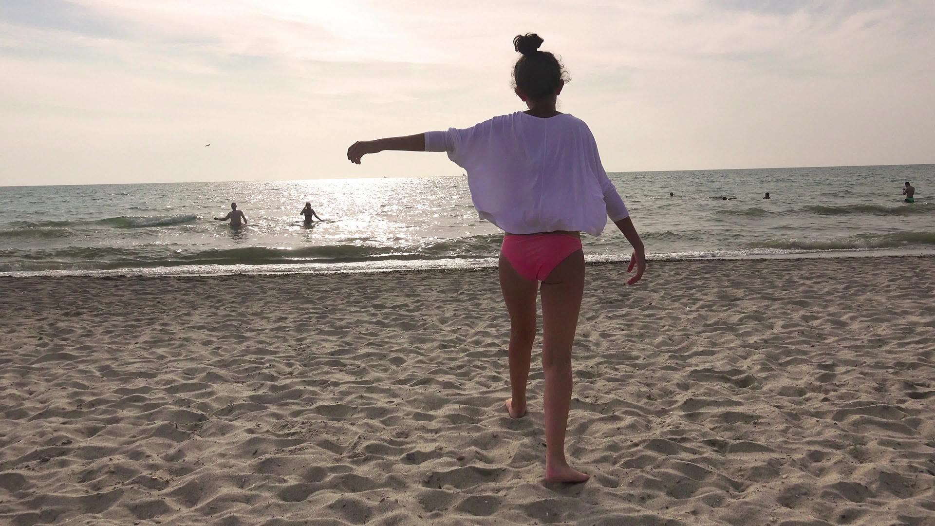 日落时海滩女孩穿着裙子跑到水边跳舞享受暑假视频的预览图
