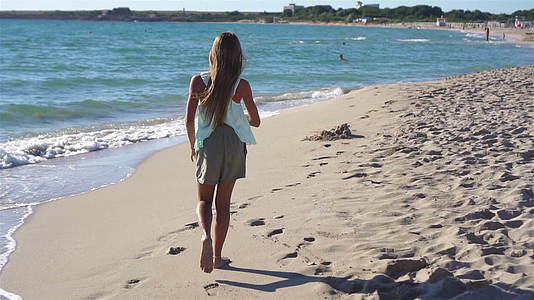 暑假期间可爱活跃的小女孩在海滩上玩耍视频的预览图