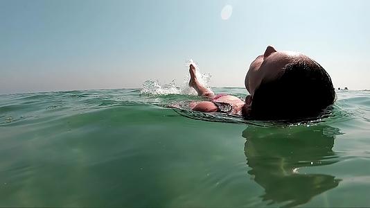 一个漂亮的女孩在她的背上慢慢地游泳视频的预览图