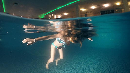 女孩沉浸在暗池表面的水下风景中视频的预览图