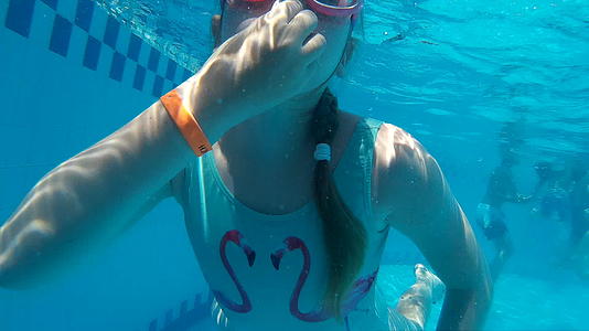 小女孩在游泳池里戴着潜水护目镜游泳视频的预览图