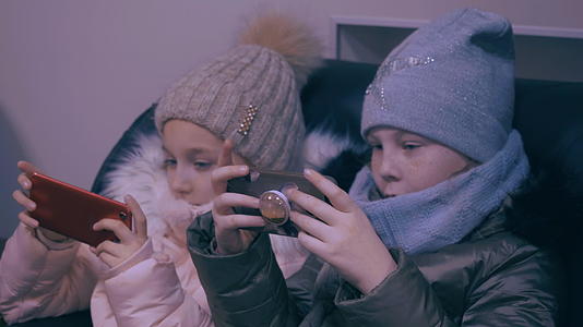 两个穿着冬装的女孩看着手机玩游戏视频的预览图