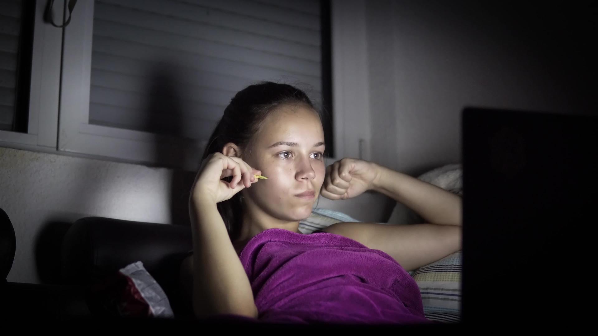 在黑暗中看电影和吃薯片的女孩视频的预览图