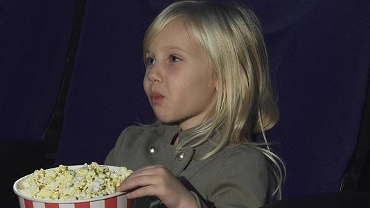 一个可爱的小女孩在电影院吃爆米花视频的预览图