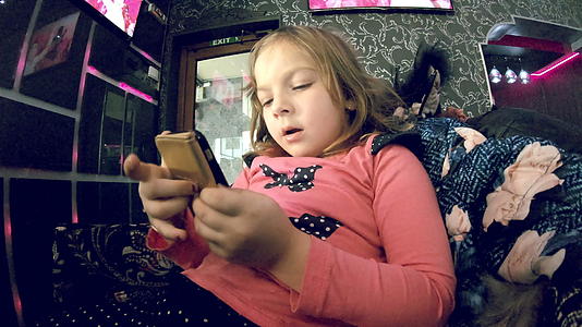 小女孩在室内智能手机上看卡通慢动作视频的预览图