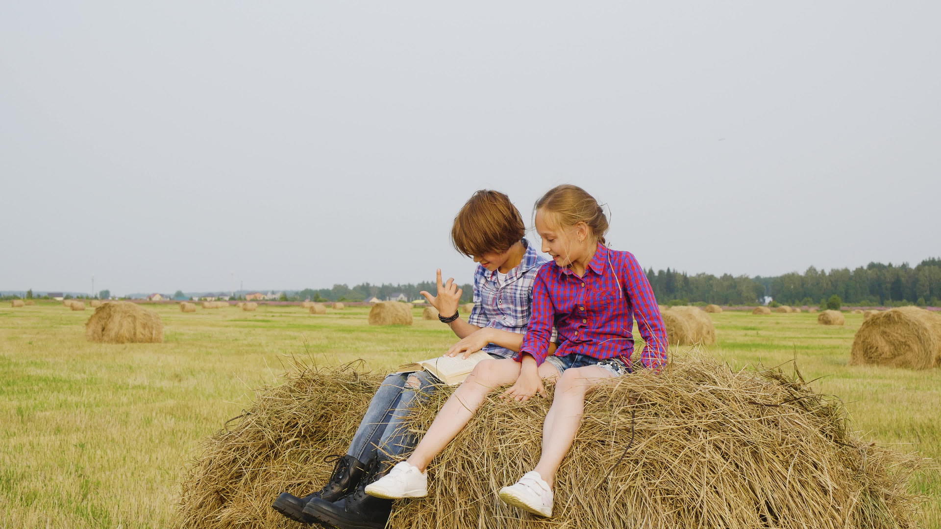 女孩和男孩青少年坐在收割场的干草堆上视频的预览图
