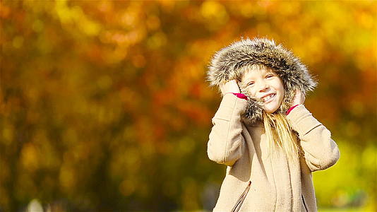 可爱的小女孩在秋天有黄树背景视频的预览图